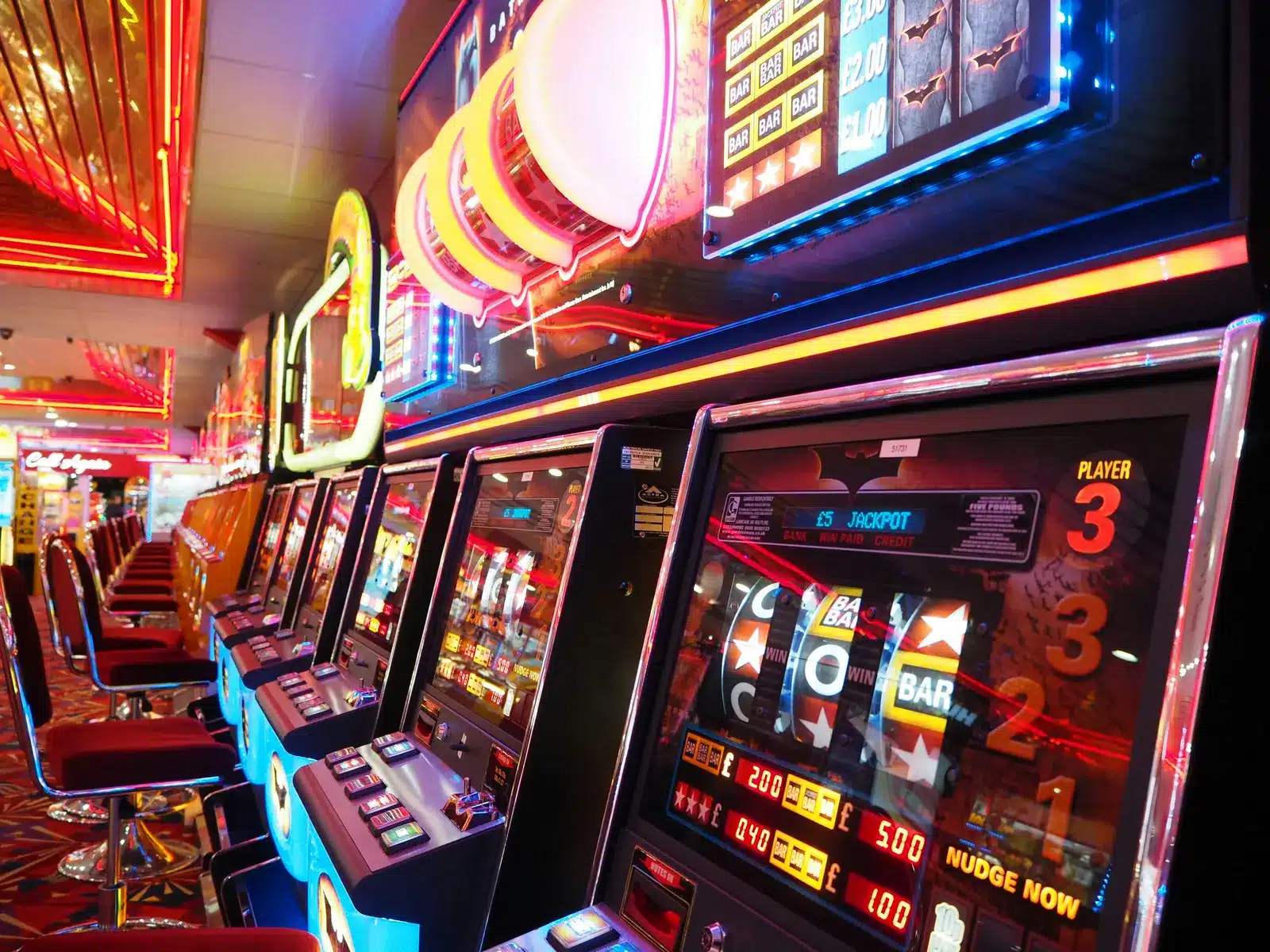 A row of brightly lit electronic gaming machines with digital displays in a casino.
